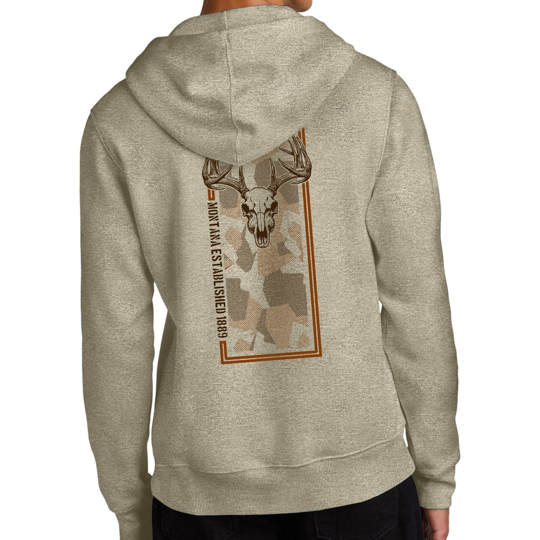 Cream-colored Big Buck Skull - Mid Weight Fleece Hoodie made in Montana by Blue Peak Creative featuring a bold, brown deer skull over muted camo and the text, 'Montana Established 1889'