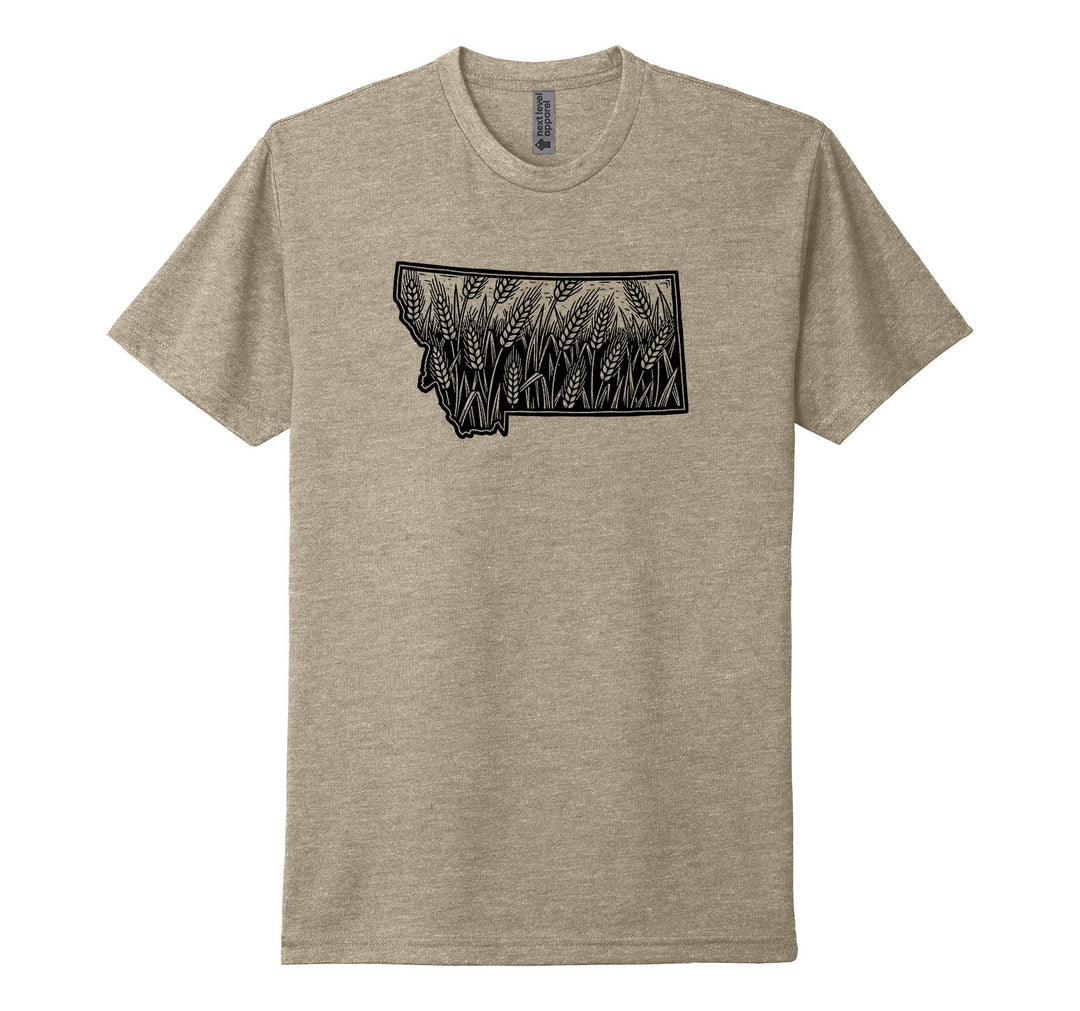 Heather tan Next Level Apparel unisex tee featuring an illustration of the outline of the state of Montana filled with a detailed illustration of wheat, swaying in the wind, designed and printed in Montana by Blue Peak Creative