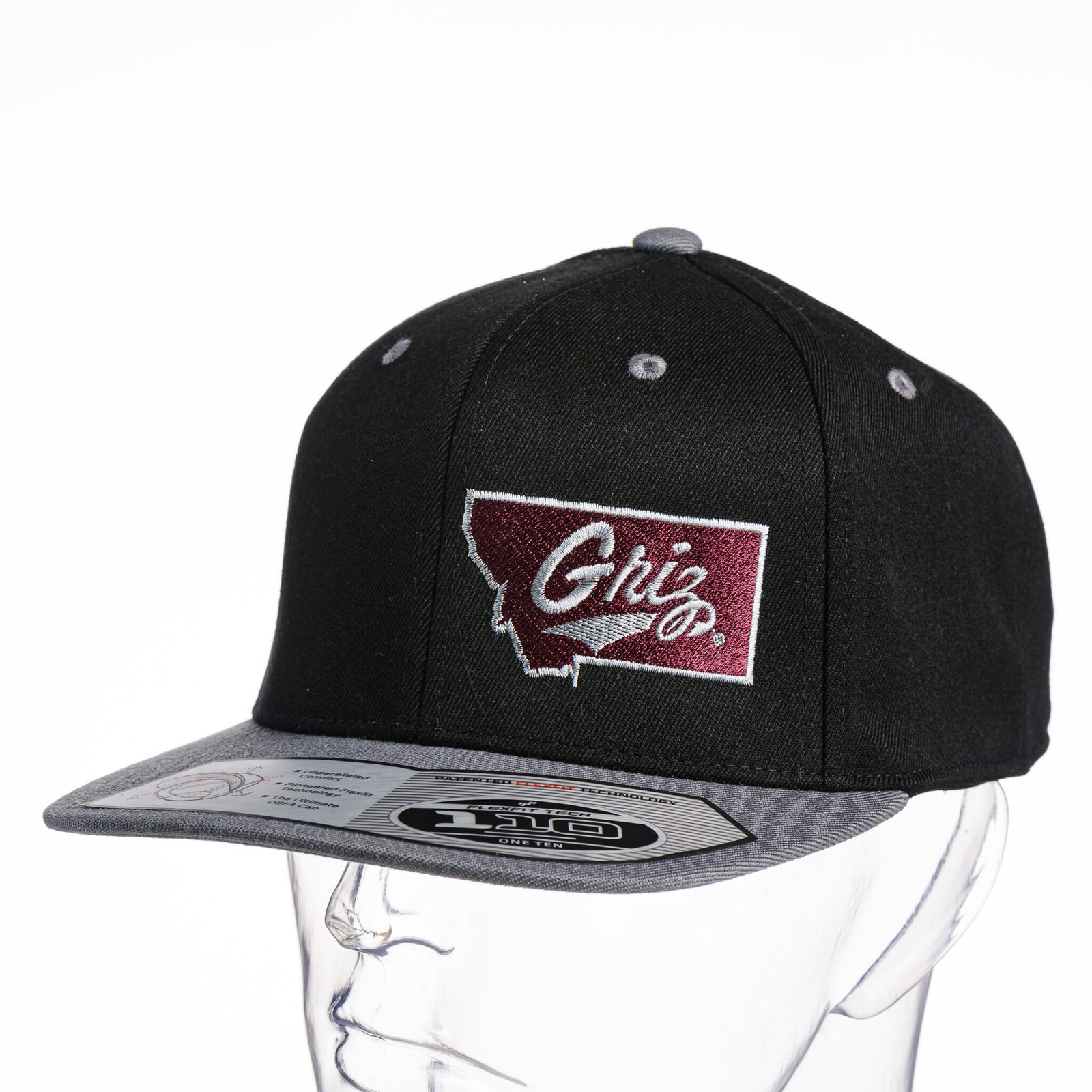 Black Montana Griz Script - Flat Bill Hat made in Missoula, MT (home of the UM Grizzlies) by Blue Peak Creative—a black flat bill hat embroidered with the University of Montana Griz script inside the outlined silhouette of the state of Montana (3/4 view).
