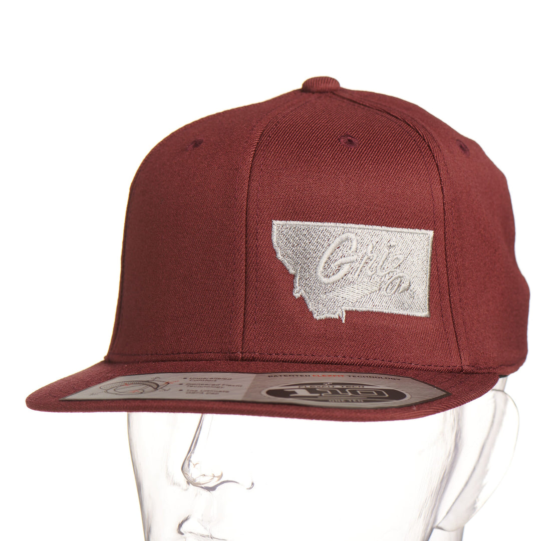 Maroon Montana Griz Script - Flat Bill Hat made in Missoula, MT (home of the UM Grizzlies) by Blue Peak Creative—a maroon flat bill hat embroidered with the University of Montana Griz script inside the outlined silhouette of the state of Montana (front).