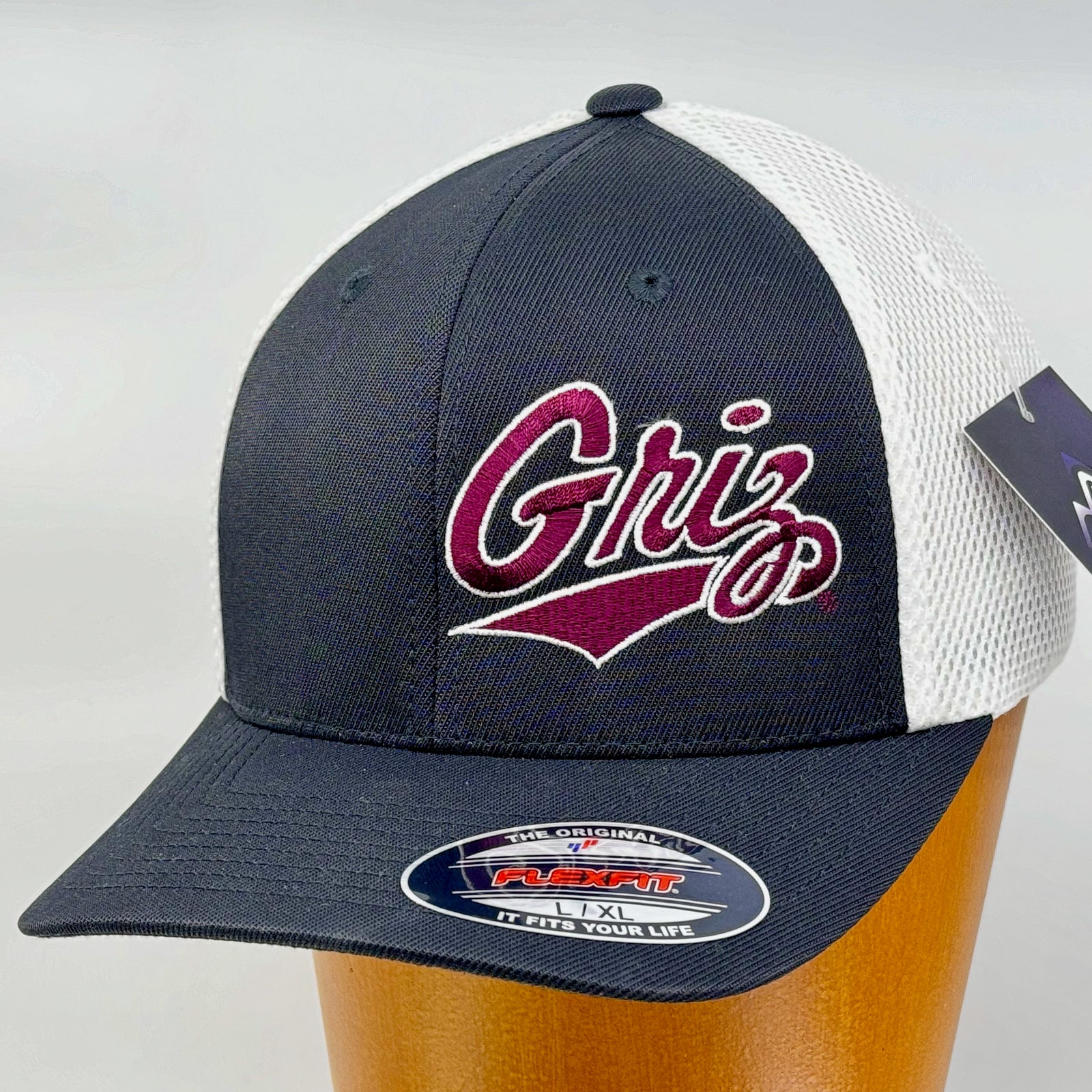Black and white Outlined Griz Script - Ultrafibre and Airmesh Flexfit Hat made in Missoula, MT (home of the UM Grizzlies) by Blue Peak Creative—a black and white Ultrafibre and Airmesh Flexfit Hat embroidered with the Outlined Griz Script in maroon and white (3/4 view)