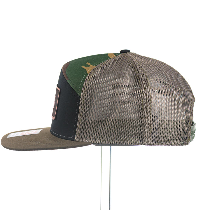 Trucker hat with mesh back and UM Griz Leather Patch front panel on a white background