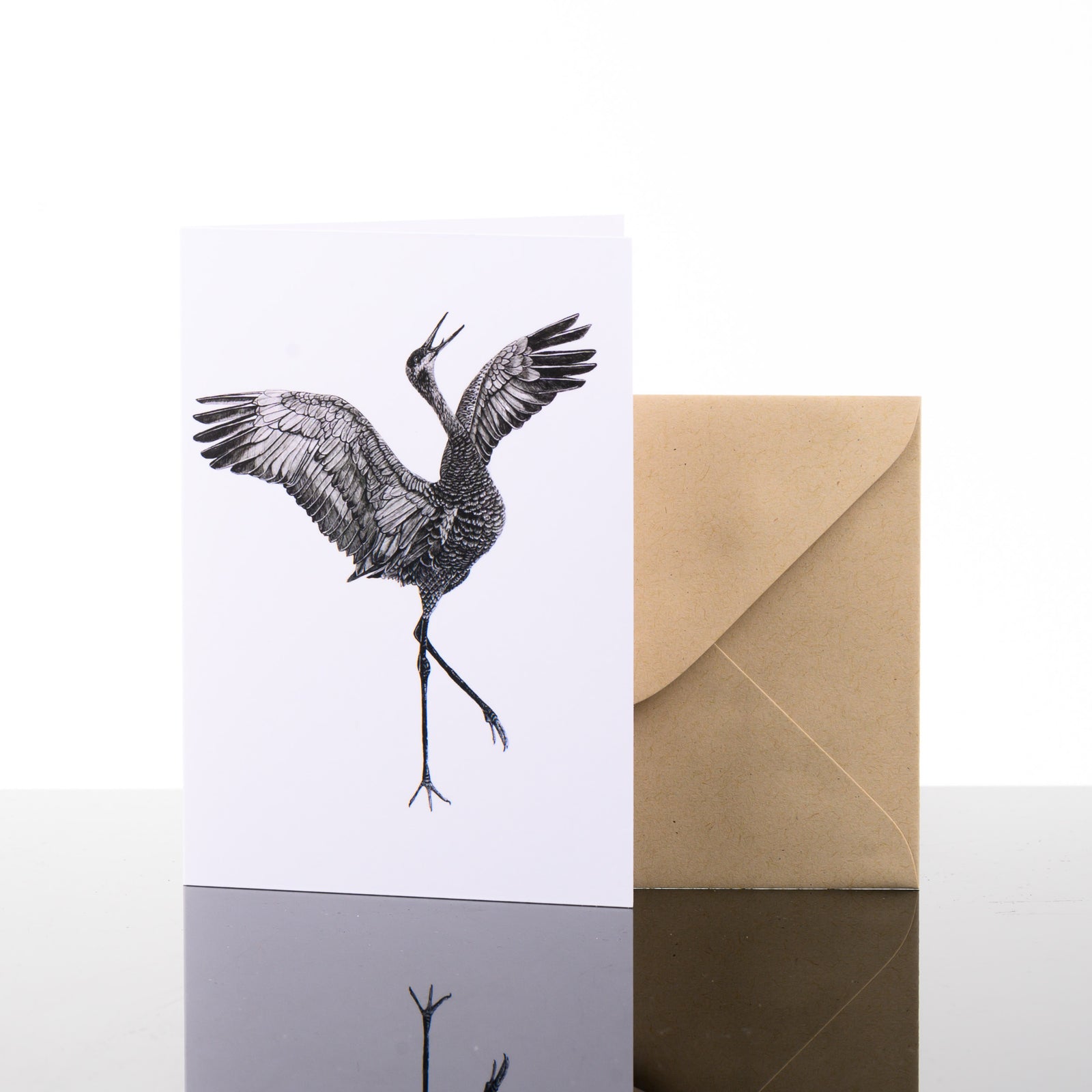 Blank greeting card featuring original black and white artwork by Brittany Finch - a graceful sandhill crane, wings spread - and kraft brown envelope by Brittany Finch Art in Montana