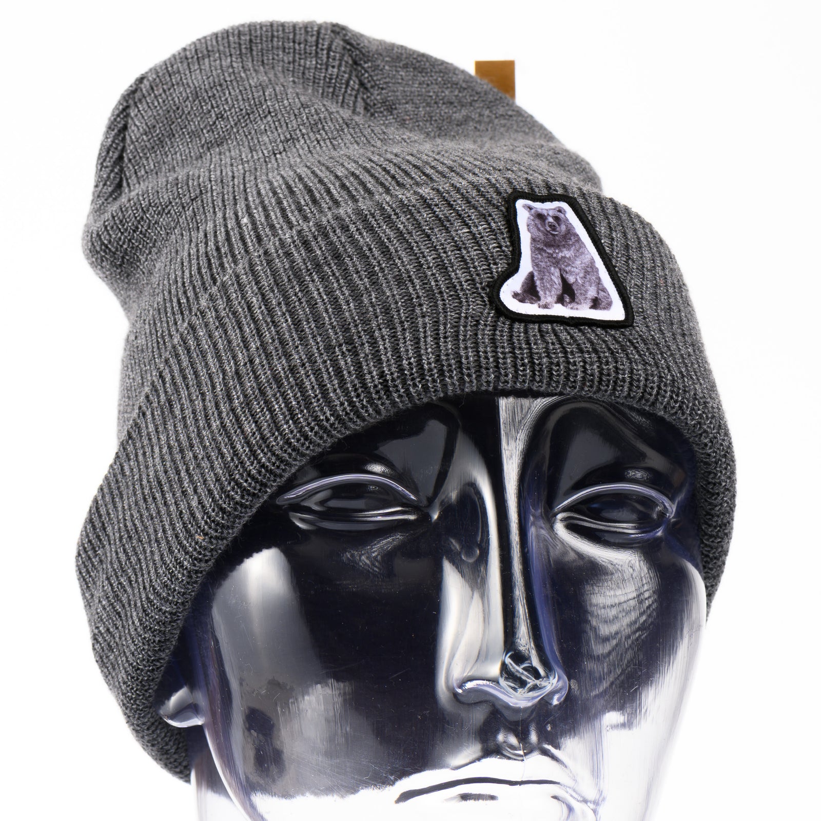 Gray beanie with a hand drawn bear patch on a mannequin head against a white background