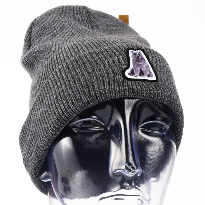 Gray beanie with a hand drawn bear patch on a mannequin head against a white background