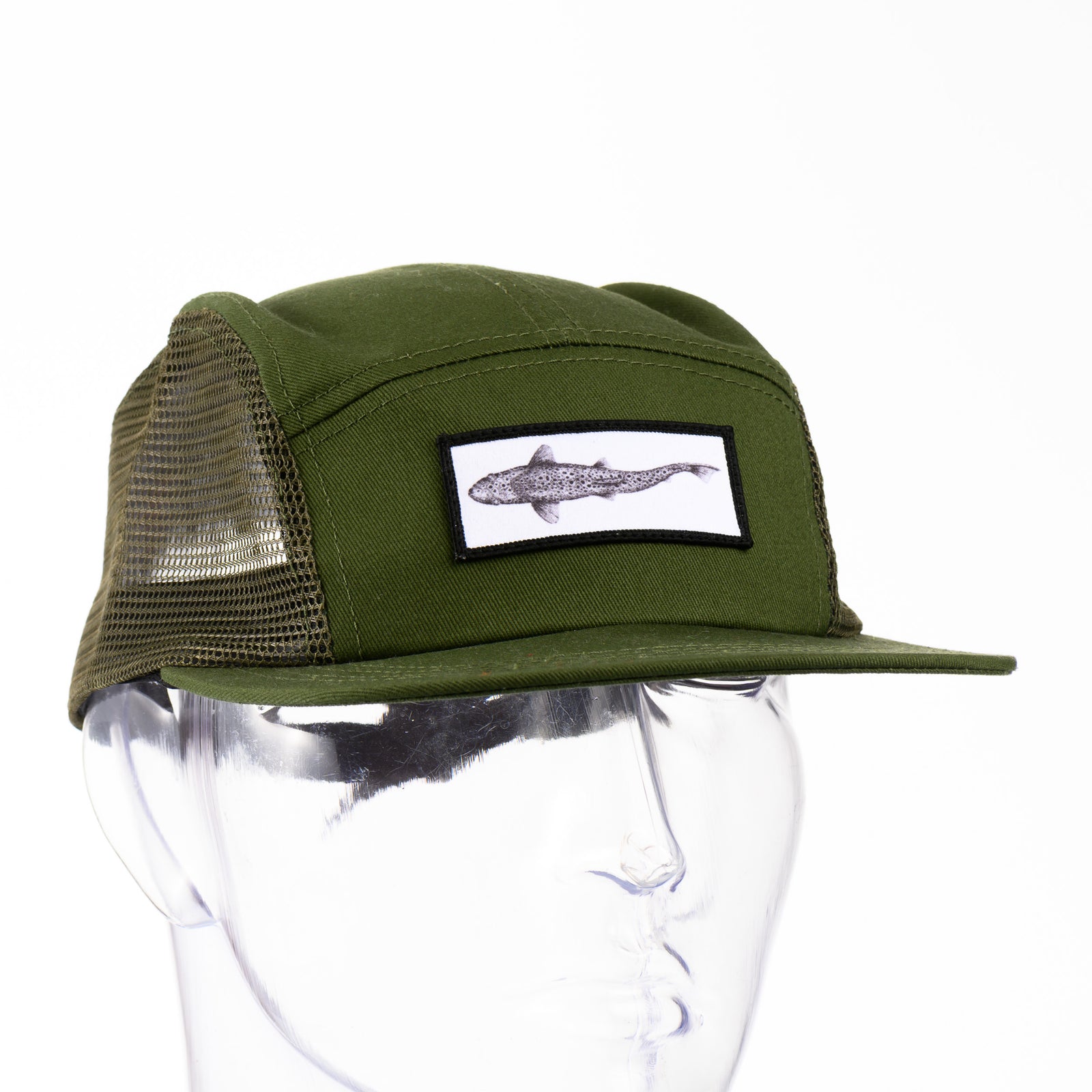 Front of a green adjustable mesh-sided cap with a patch featuring original black and white artwork by Brittany Finch -  a swimming brown trout viewed from above -  made in Montana by Brittany Finch Art and displayed on a mannequin head 