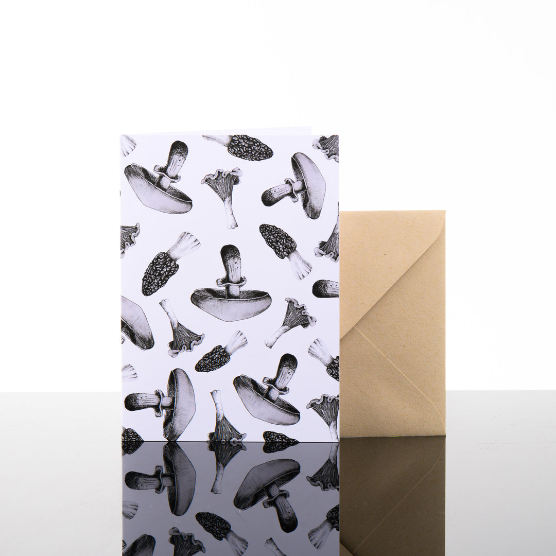 Blank greeting card featuring original black and white artwork by Brittany Finch - a collage of assorted wild mushrooms - and kraft brown envelope by Brittany Finch Art in Montana