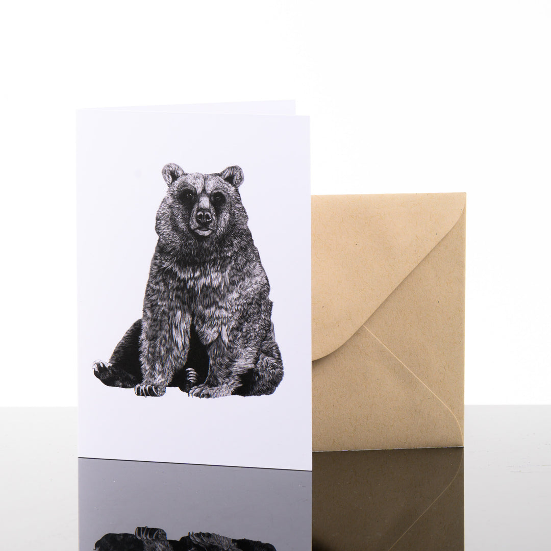 Blank greeting card featuring original black and white artwork by Brittany Finch - a serene bear, sitting on its haunches - and kraft brown envelope by Brittany Finch Art in Montana