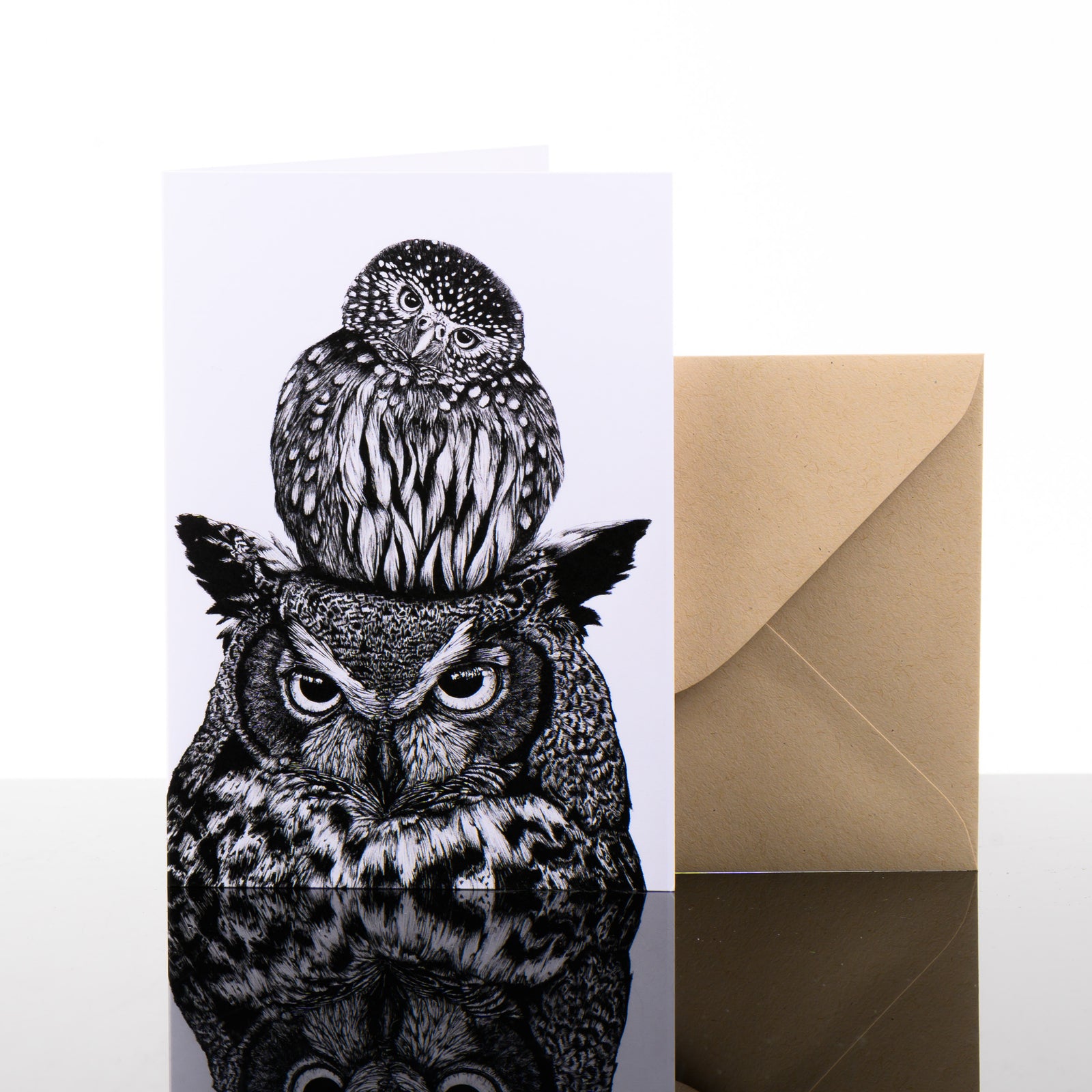 Unlikely Friends Greeting Card featuring black and white drawings by Montana artist Brittany Finch (a small owl perched on top of the head of a great horned owl) with kraft brown envelope; blank greeting card made in Montana, USA