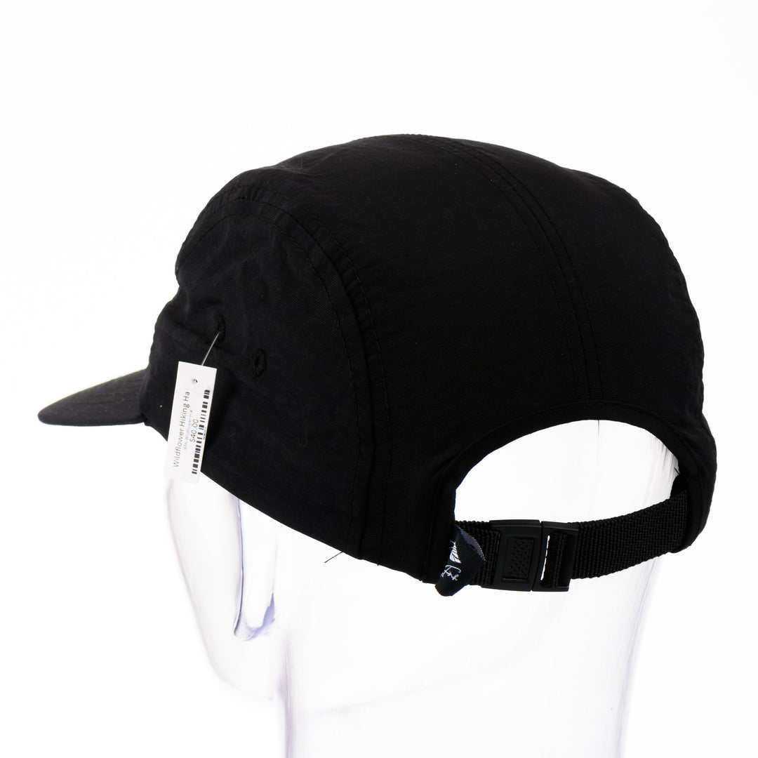 Back of a black 5-panel hat with a brim featuring original black and white artwork by Brittany Finch -  wildflowers stretched across the front panel -  made in Montana by Brittany Finch Art and displayed on a mannequin head 