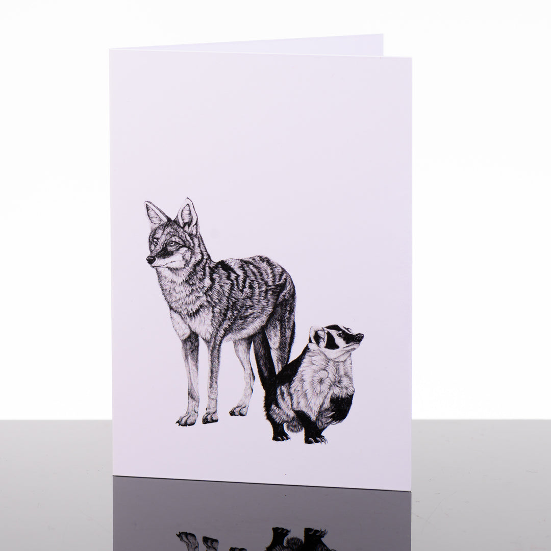 Blank greeting card featuring original black and white artwork by Brittany Finch - a coyote and a badger, standing side-by-side - made in Montana by Brittany Finch Art