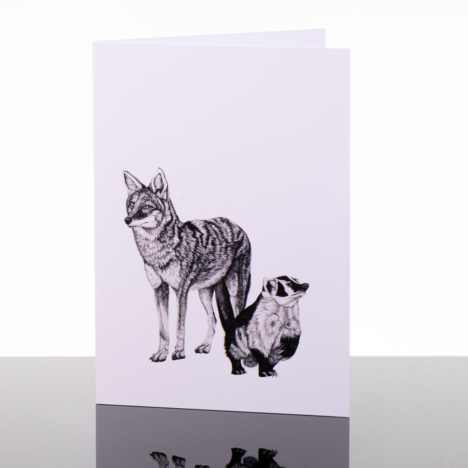 Blank greeting card featuring original black and white artwork by Brittany Finch - a coyote and a badger, standing side-by-side - made in Montana by Brittany Finch Art