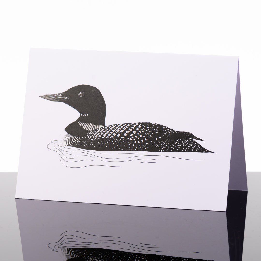 Blank greeting card featuring original black and white artwork by Brittany Finch - a loon floating in rippling water - made in Montana by Brittany Finch Art