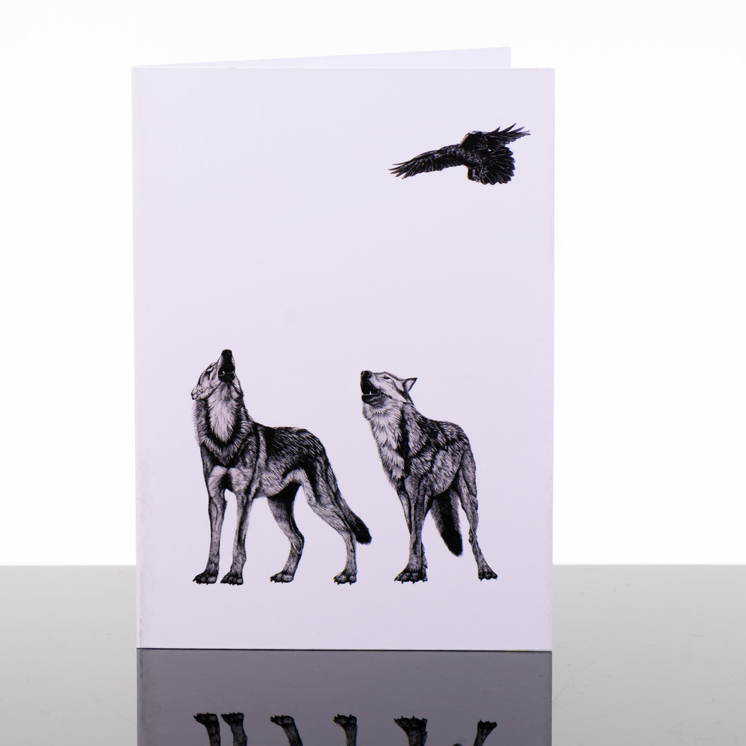 Blank greeting card featuring original black and white artwork by Brittany Finch - two howling wolves beneath a soaring raven - made in Montana by Brittany Finch Art