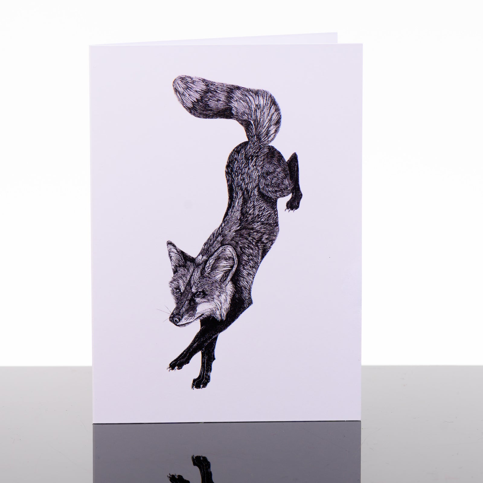 Blank greeting card featuring original black and white artwork by Brittany Finch - a dynamic red fox, on a descending leap - by Brittany Finch Art in Montana