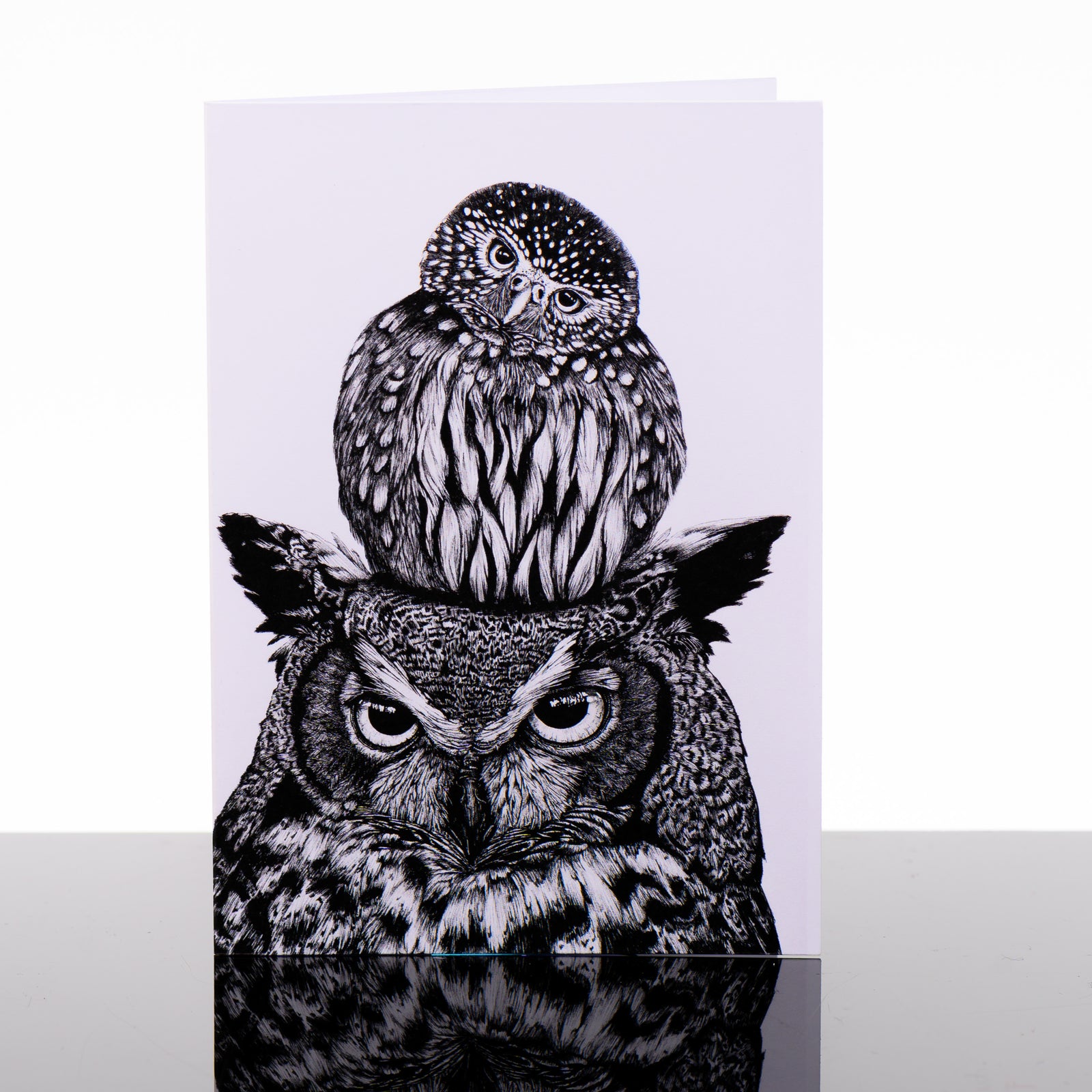Unlikely Friends Greeting Card featuring black and white drawings by Montana artist Brittany Finch (a small owl perched on top of the head of a great horned owl); blank greeting card made in Montana, USA