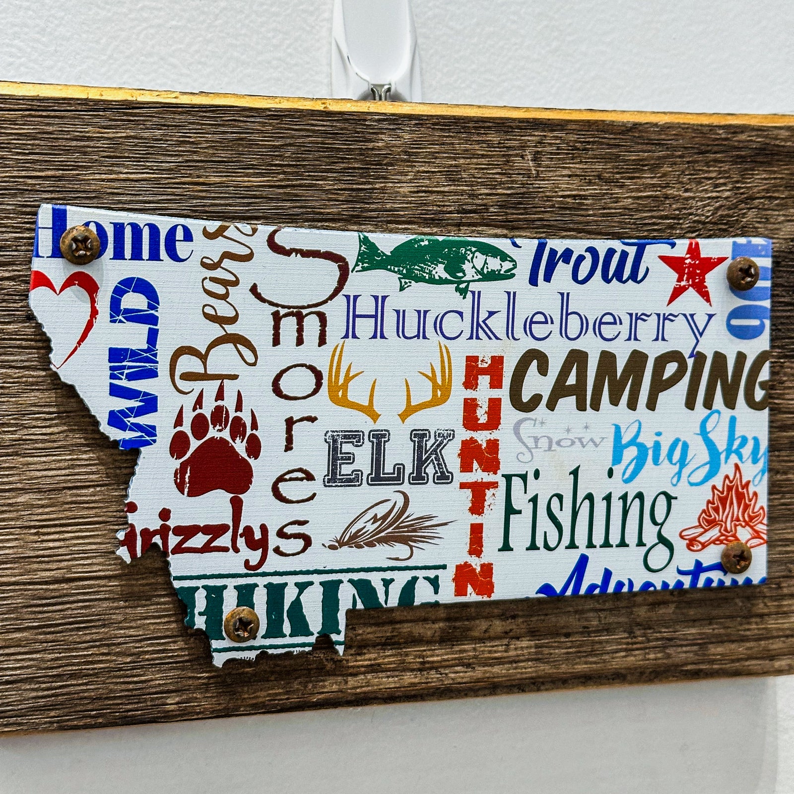 This Montana shaped art is a piece of printed metal screwed onto a piece of wood. Made in Montana, USA