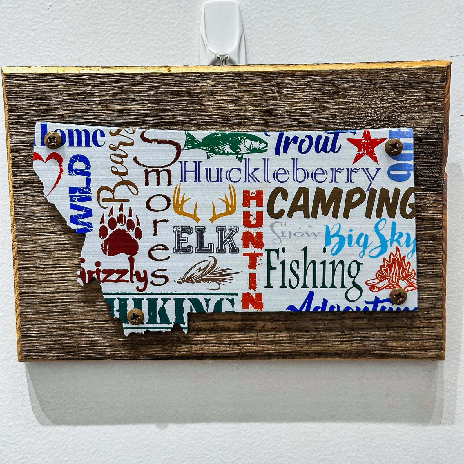 This Montana shaped art is a piece of printed metal screwed onto a piece of wood. Made in Montana, USA