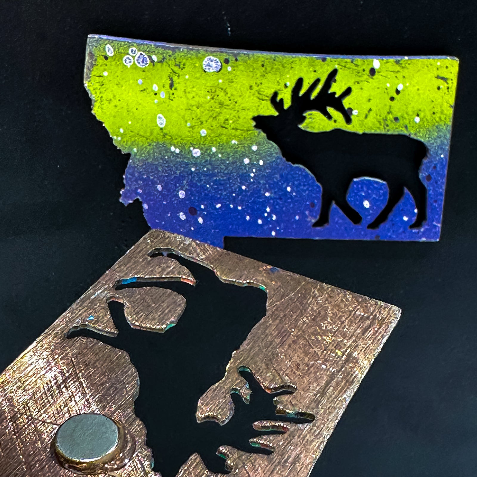 A made in Montana state-shaped cut-out with an elk bugling silhouette embedded in it and a strong back magnet.