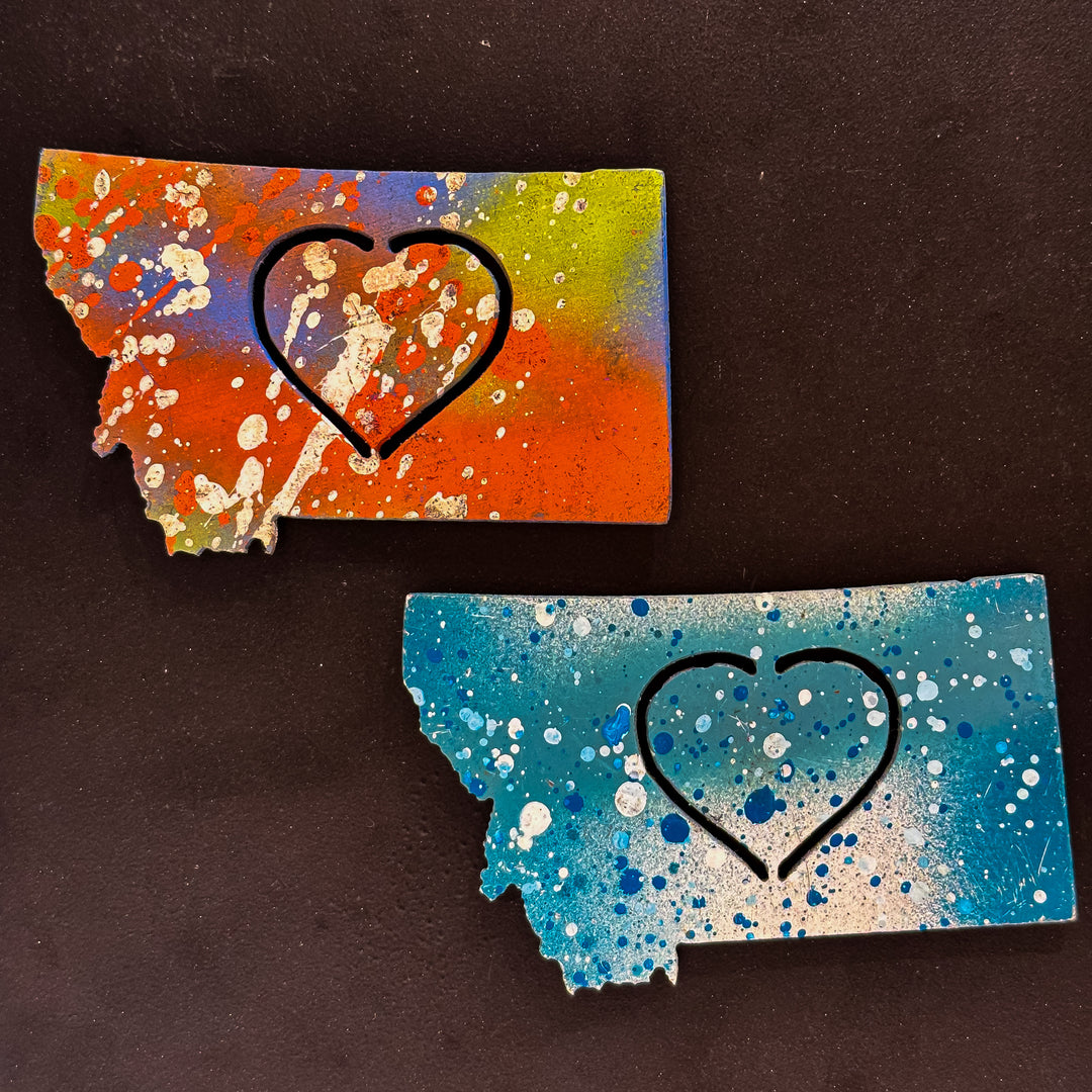 A made in Montana state-shaped cut-out with a heart silhouette embedded in it and a strong back magnet.