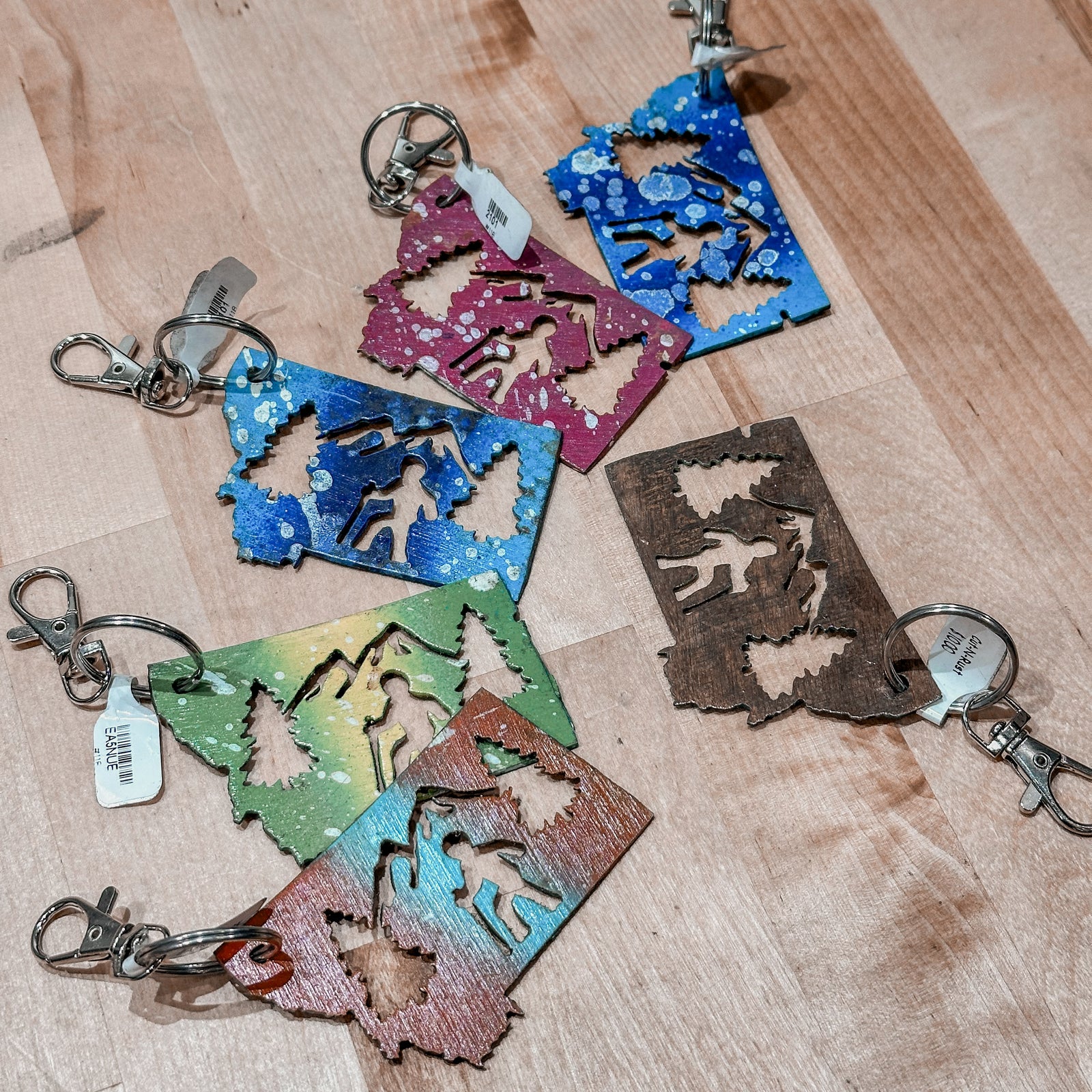 This made in Montana Hiker Metal Keychain showcases a state-shaped design with a hiker, mountains and trees cut out of it.