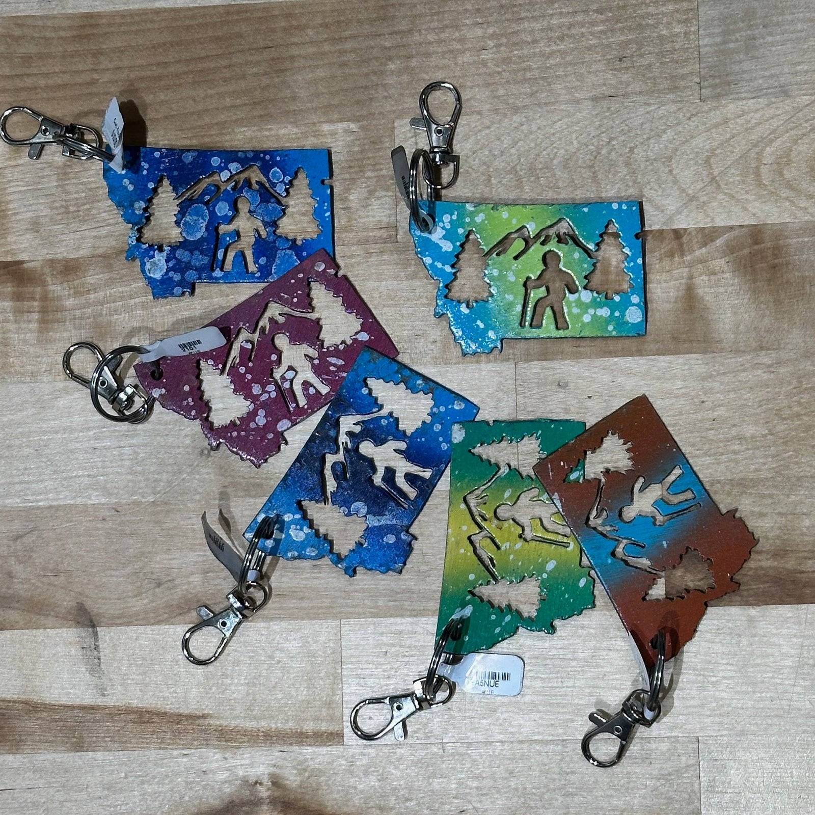 This made in Montana Hiker Metal Keychain showcases a state-shaped design with a hiker, mountains and trees cut out of it.