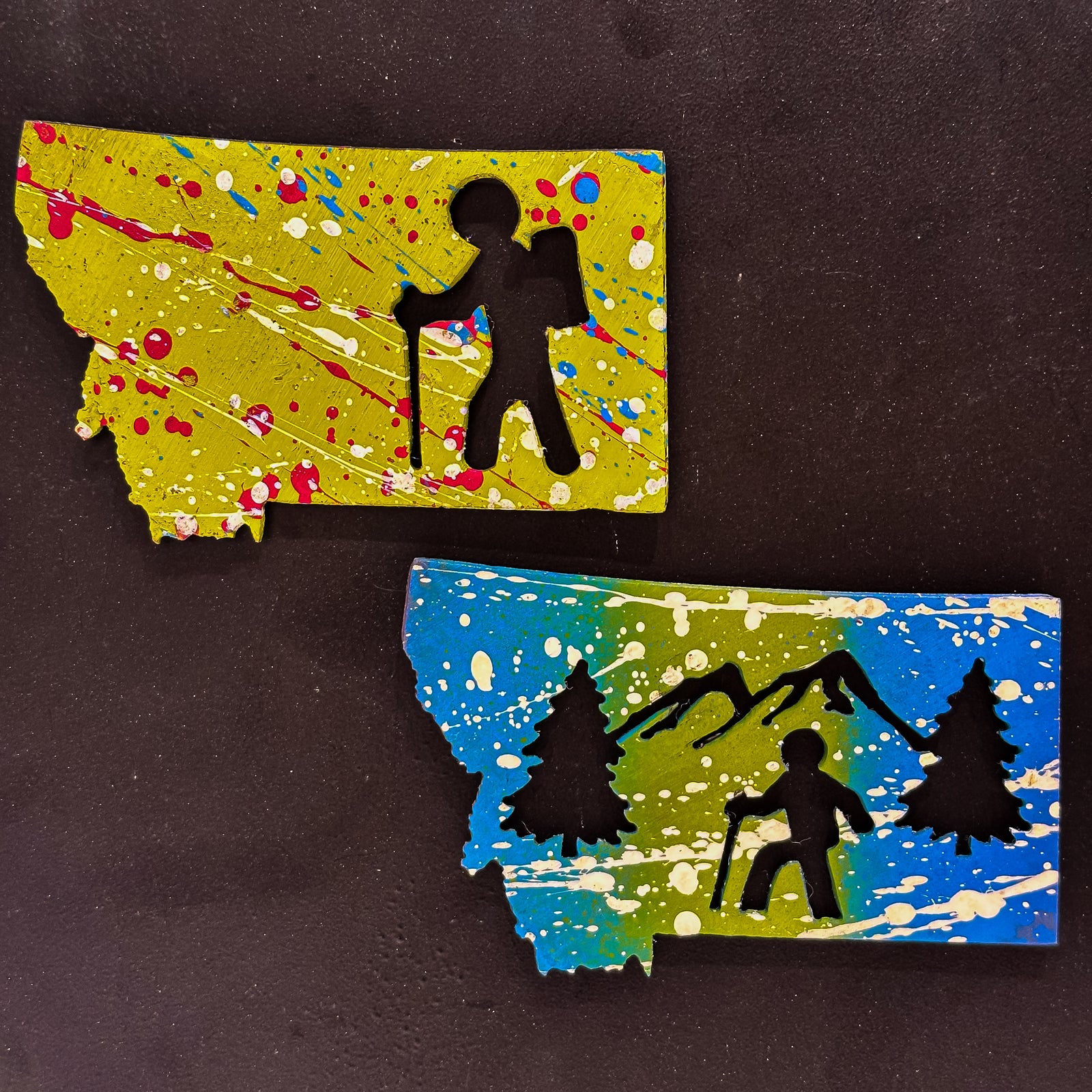 A made in Montana state-shaped cut-out with silhouettes of hikers embedded in it and a strong back magnet.