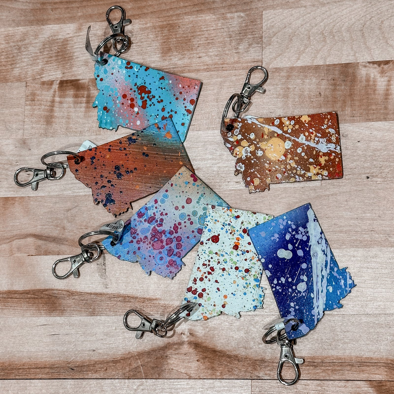 This made in Montana Metal Keychain showcases a state-shaped design with various paint splatter colors