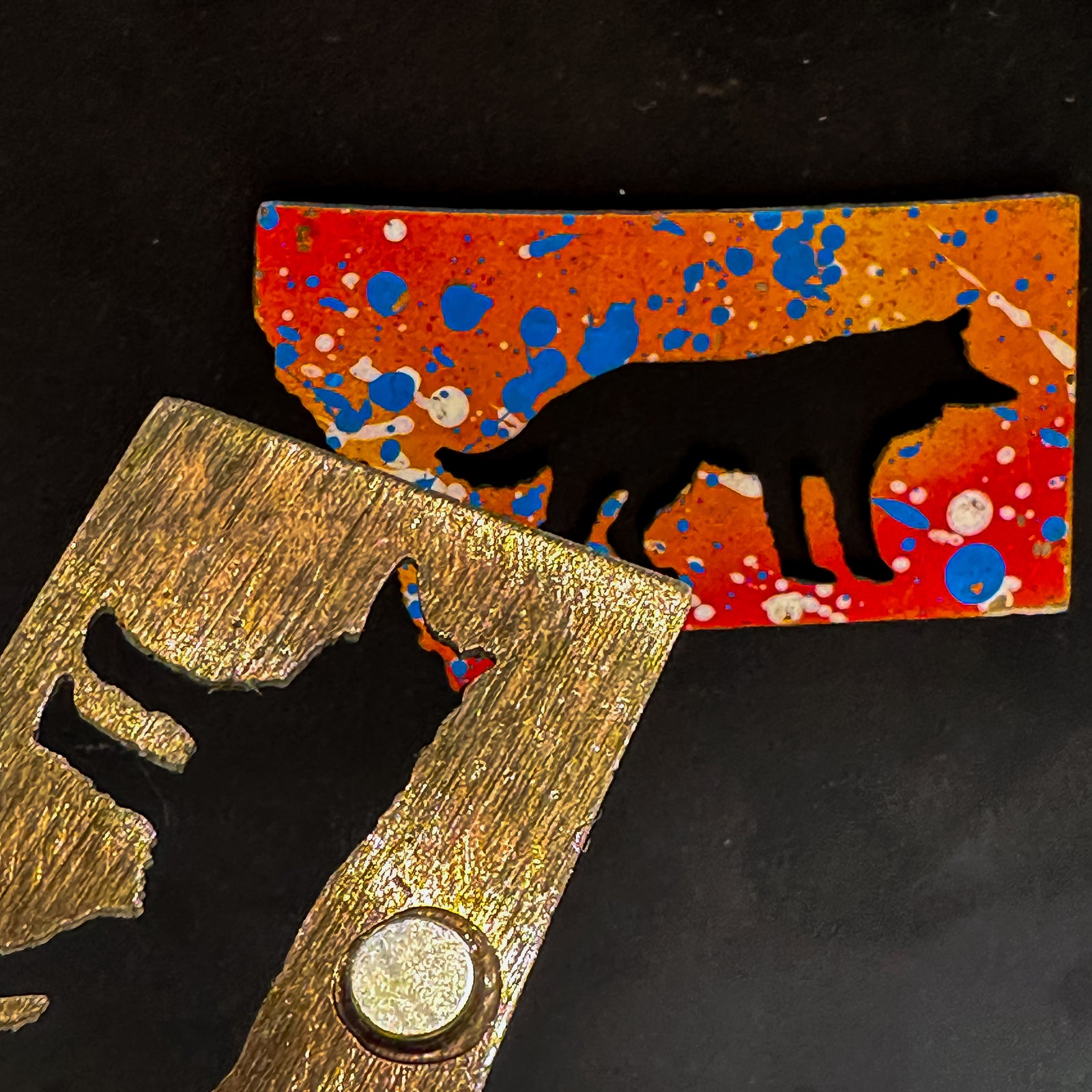 A made in Montana state-shaped cut-out with a silhouette of a wolf embedded in it and a strong back magnet.