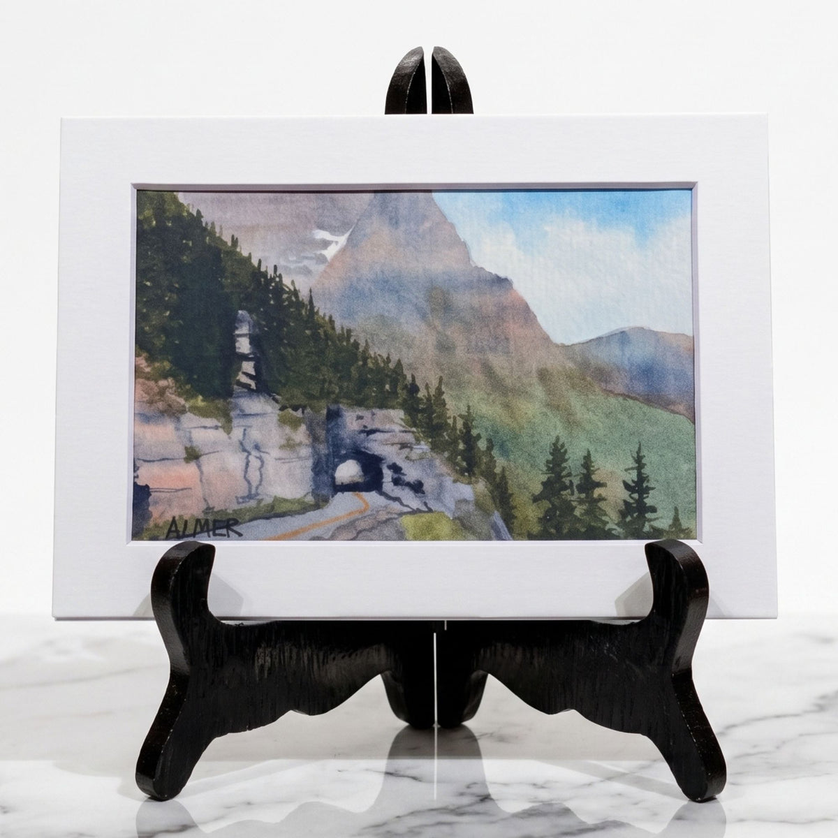 Experience Glacier National Park’s rugged beauty with this matted 5x7 Bobbe Almer watercolor print of the iconic tunnel view from the Sun Road.
