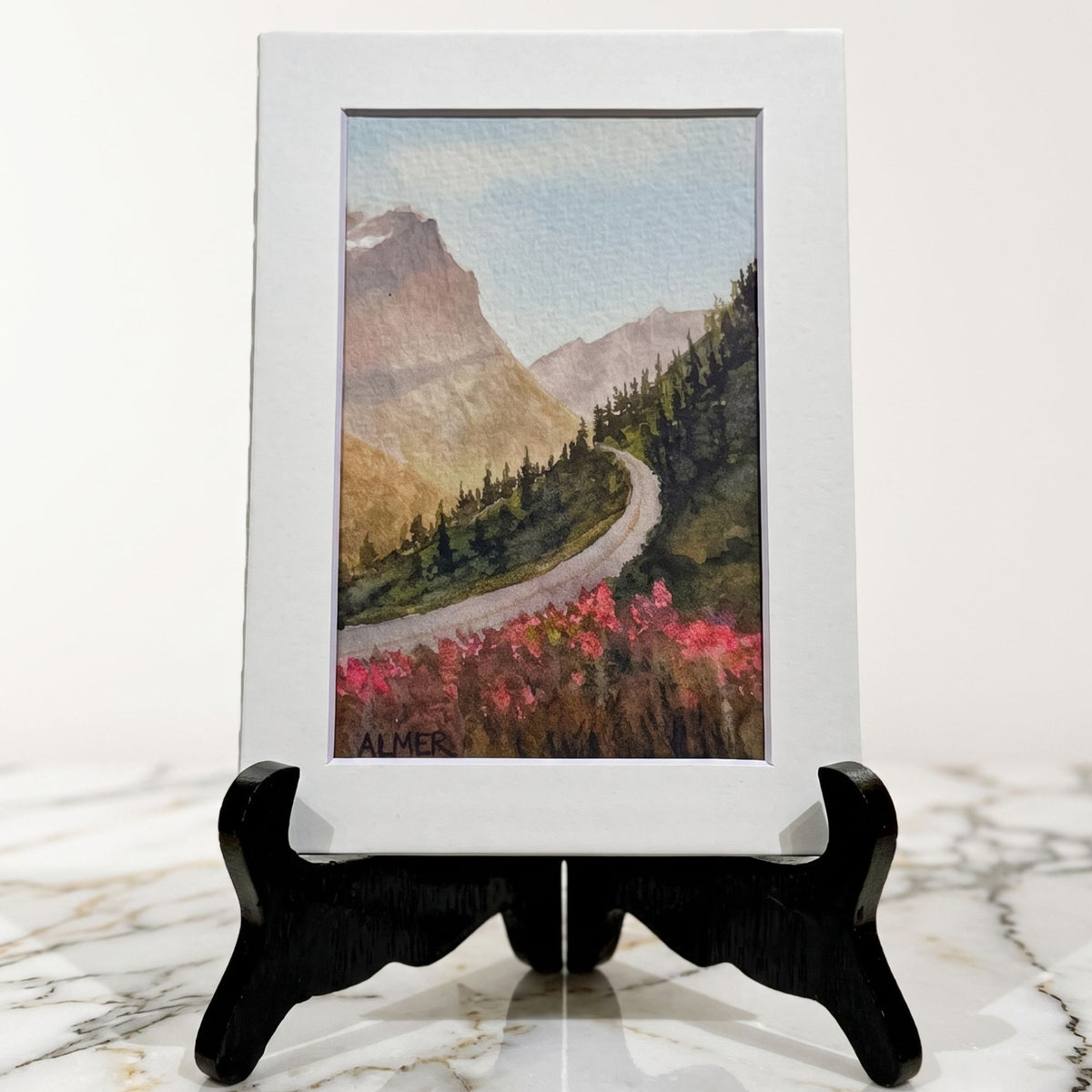 Bring home the magic of dusk with the Golden Hour 5x7 Matted Print by Stark Mountain Studio. Beautiful watercolor artwork of scenic Montana mountain roads.