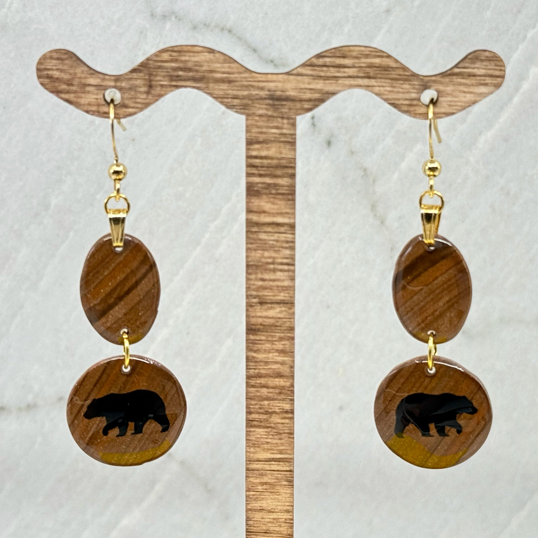 Pair of Small Dangle Earrings with Bears by Bitterroot Shining Creations, featuring double drop polymer clay in in various colors with a bear silhouette on the bottom drop (brown), hanging