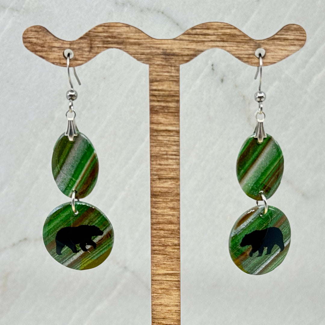 Pair of Small Dangle Earrings with Bears by Bitterroot Shining Creations, featuring double drop polymer clay in in various colors with a bear silhouette on the bottom drop (green), hanging