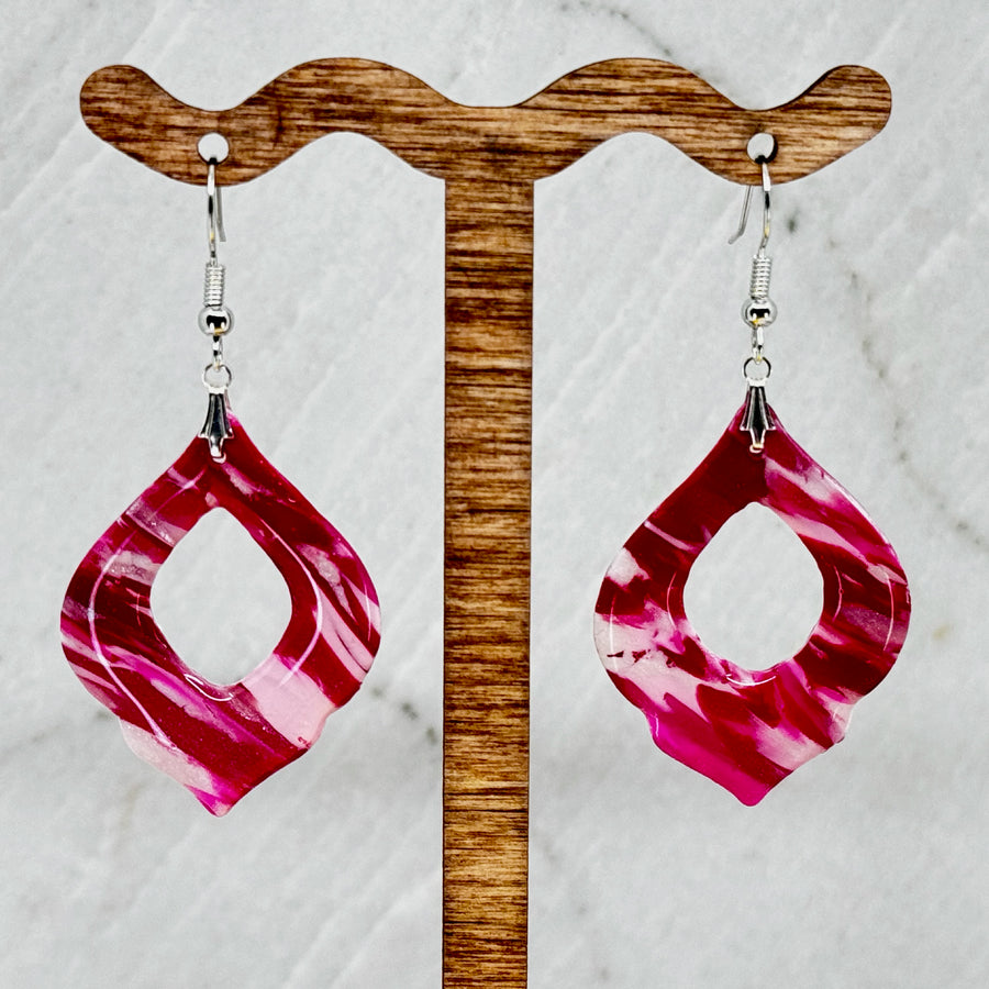 Pair of Pink and Red Arabesquee Earrings by Bitterroot Shining Creations, featuring marbleized pink and red polymer clay, hanging