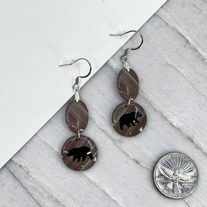 Pair of Small Dangle Earrings with Bears by Bitterroot Shining Creations, featuring double drop polymer clay in in various colors with a bear silhouette on the bottom drop (taupe), with scale
