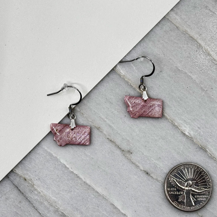 Pair of small, polymer clay Montana Earrings by Bitterroot Shining Creations in assorted sparkly colors (light pink), with scale