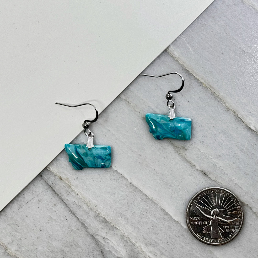 Pair of small, polymer clay Montana Earrings by Bitterroot Shining Creations in assorted sparkly colors (teal), with scale