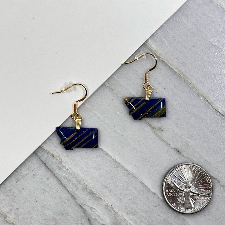 Pair of small, polymer clay Montana Earrings by Bitterroot Shining Creations in assorted sparkly colors (blue and gold), with scale