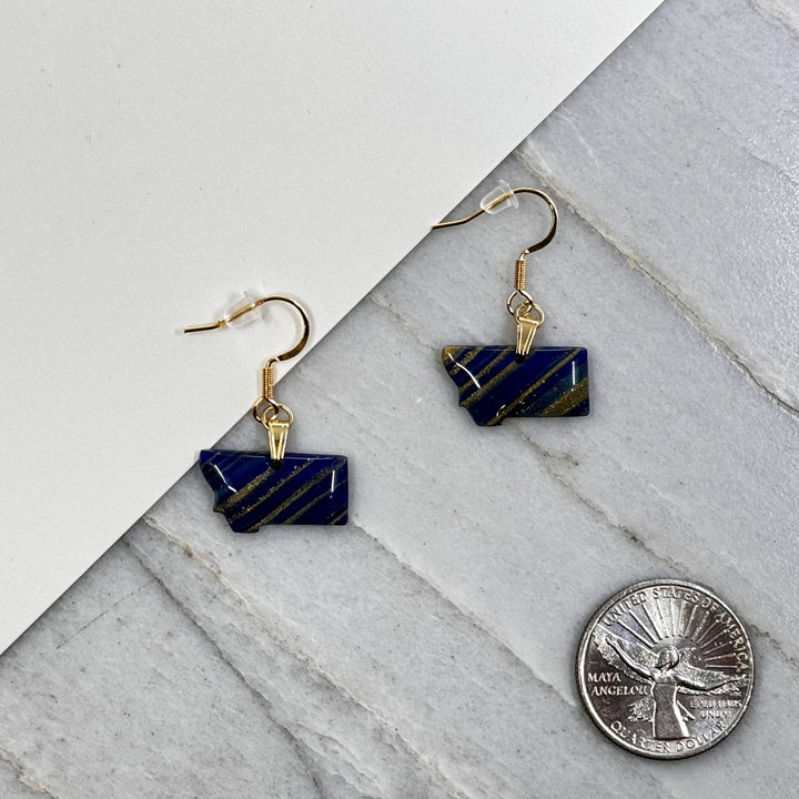 Pair of small, polymer clay Montana Earrings by Bitterroot Shining Creations in assorted sparkly colors (blue and gold), with scale