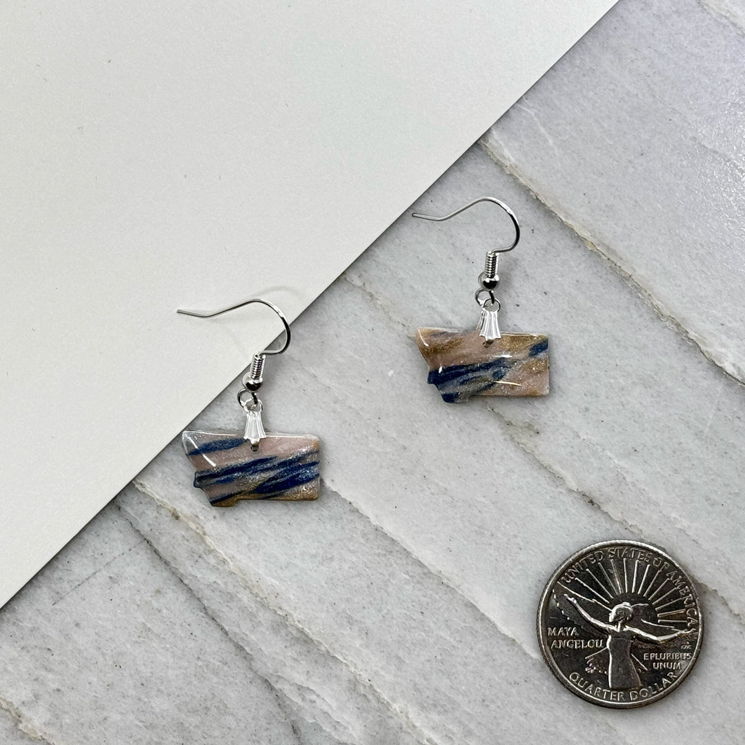 Pair of small, polymer clay Montana Earrings by Bitterroot Shining Creations in assorted sparkly colors (sky and sand), with scale