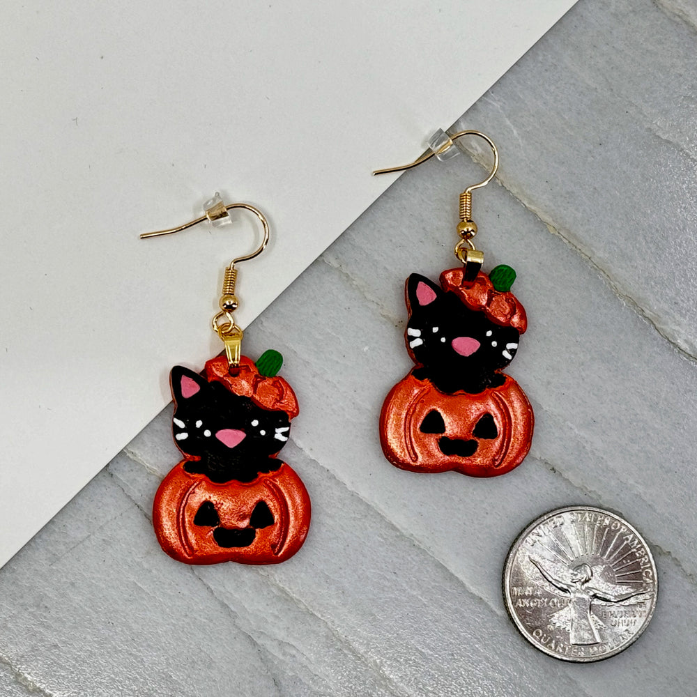 Pair of Pumpkin Cat Earrings featuring polymer clay black cats emerging from sparkly orange pumpkins, with scale
