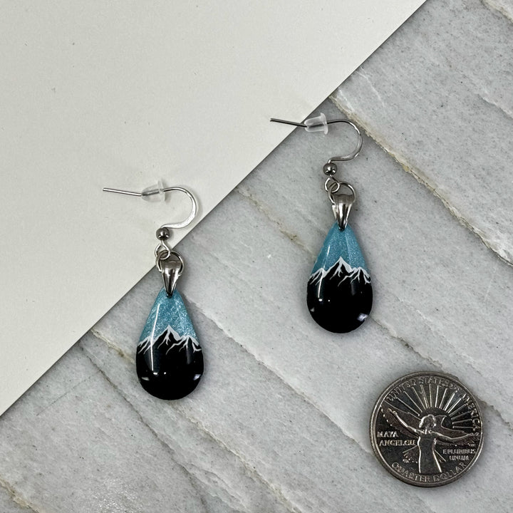 Pair of small, polymer clay Teardrop Earrings with Mountain by Bitterroot Shining Creations (sparkly light blue), with scale