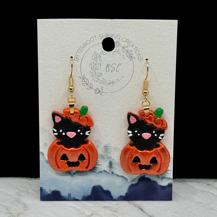 Pair of Pumpkin Cat Earrings featuring polymer clay black cats emerging from sparkly orange pumpkins, on card
