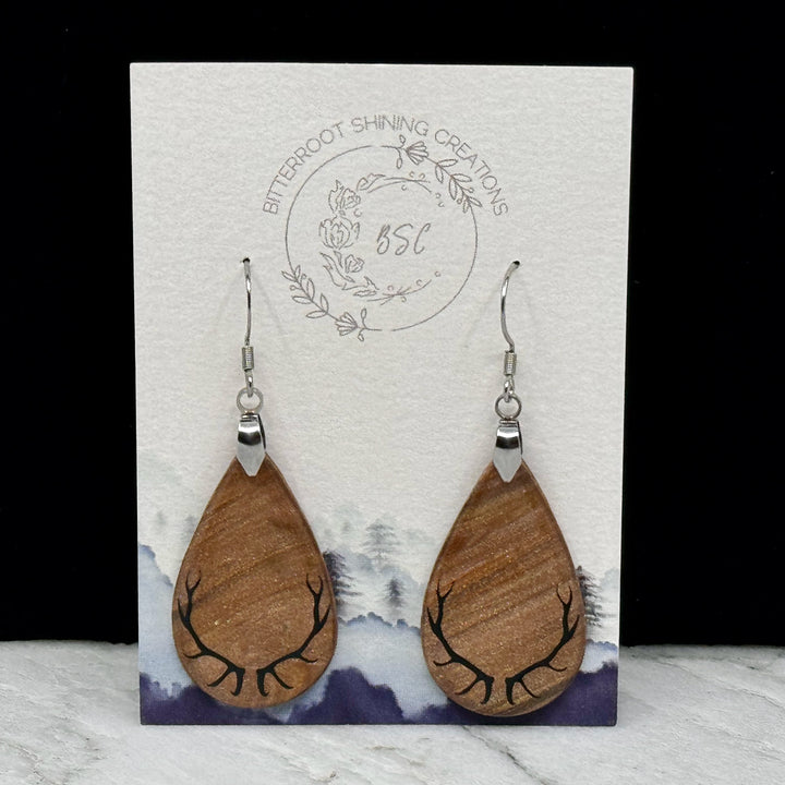 Pair of Large Teardrop Earrings with Antlers, featuring shimmering gold polymer clay teardrops decorated with black antlers, on card