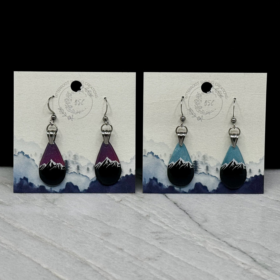 Two pairs of small, polymer clay Teardrop Earrings with Mountain by Bitterroot Shining Creations (sparkly light blue or purple), on cards