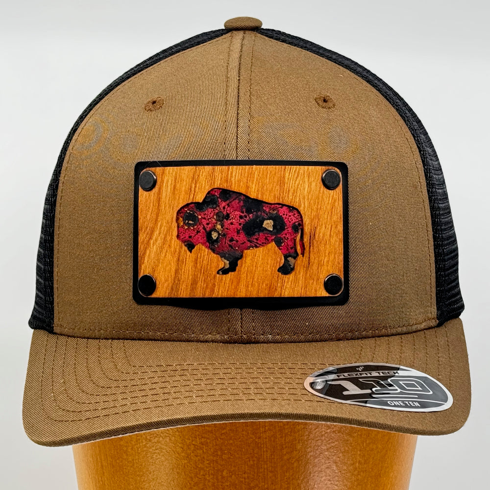 Last Best Supply Co's Cherry Wood & Red Copper Bison Coyote Brown & Black Trucker Hat, featuring an oxidized copper bison silhouette cut out of cherry wood and set against a black metal patch (front view)