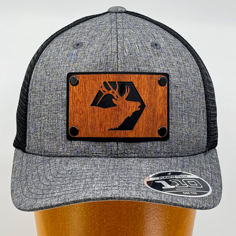 Last Best Supply Co's Mahogany Elk & Metal Patch Flexfit Trucker Hat, featuring an elk silhouette cut out of mahogany set against a black metal patch riveted to a grey and black trucker hat (front view) 