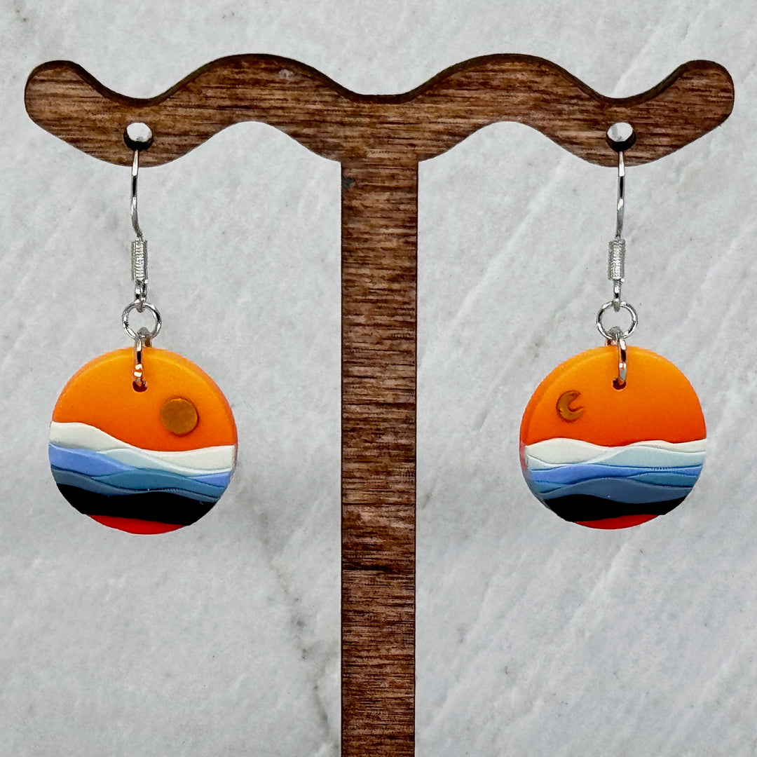 Pair of La Petite Rose's Big Sky Montana Sun Moon Landscape Clay Earrings (orange), hanging