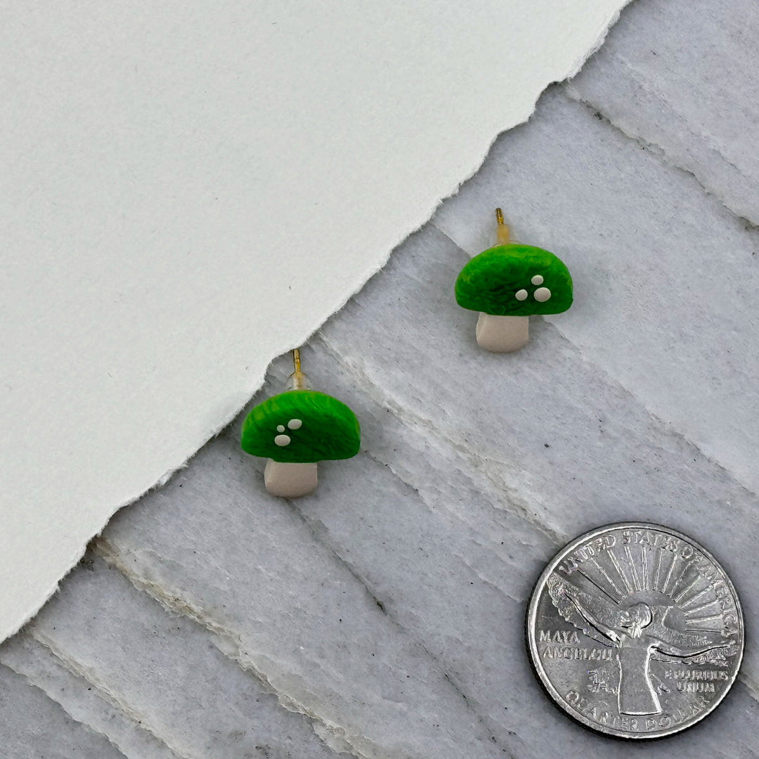 Pair of La Petite Rose Polymer Clay Green Mushroom Stud Earrings, with scale