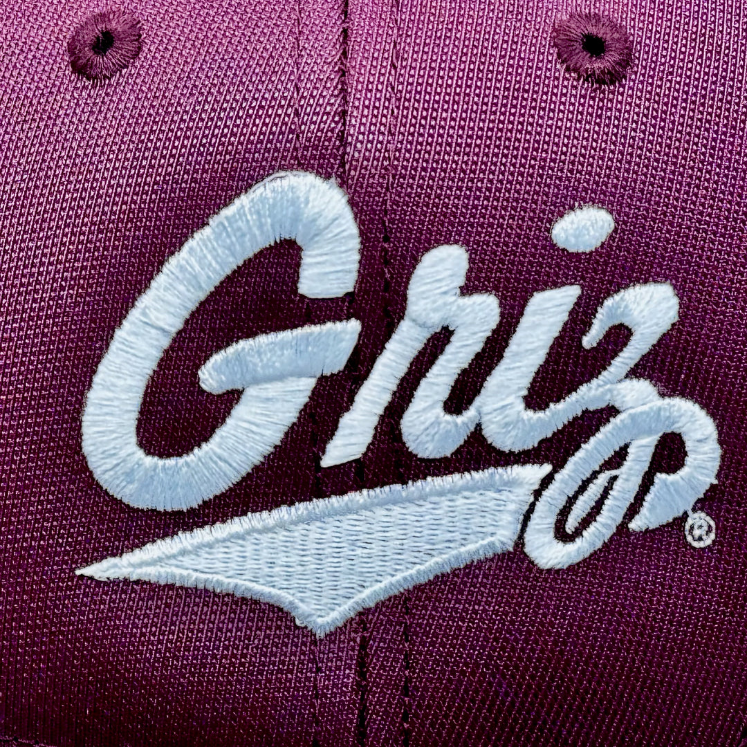 Blue Peak Creative's Youth maroon and white Sport Tek Two Tone Hat with the University of MT Griz Script embroidered in white (detail)